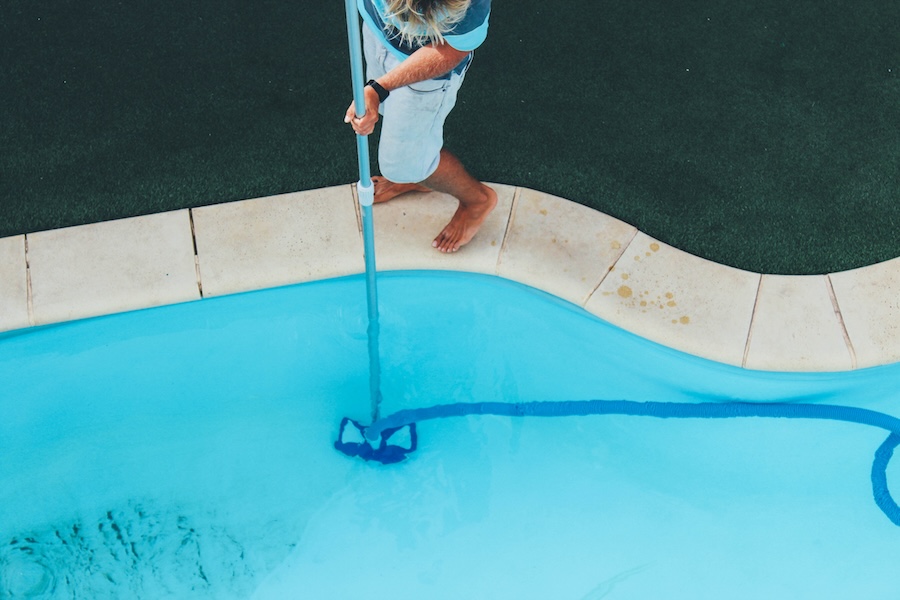 Pool guy celaning a pool with vacuum cleaner