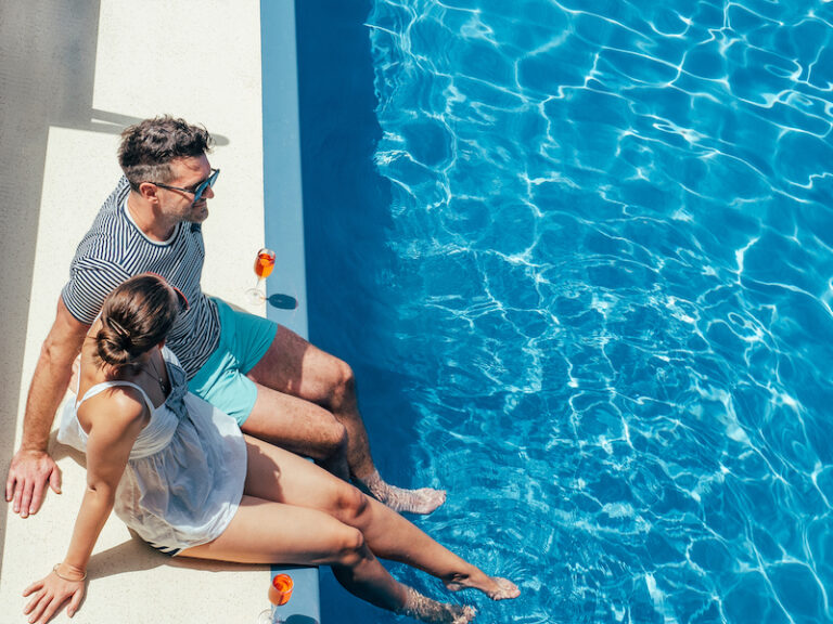 Young couple in love sitting by the pool on the empty deck of a cruise liner. Closeup, outdoor, view from above. Vacation and travel concept