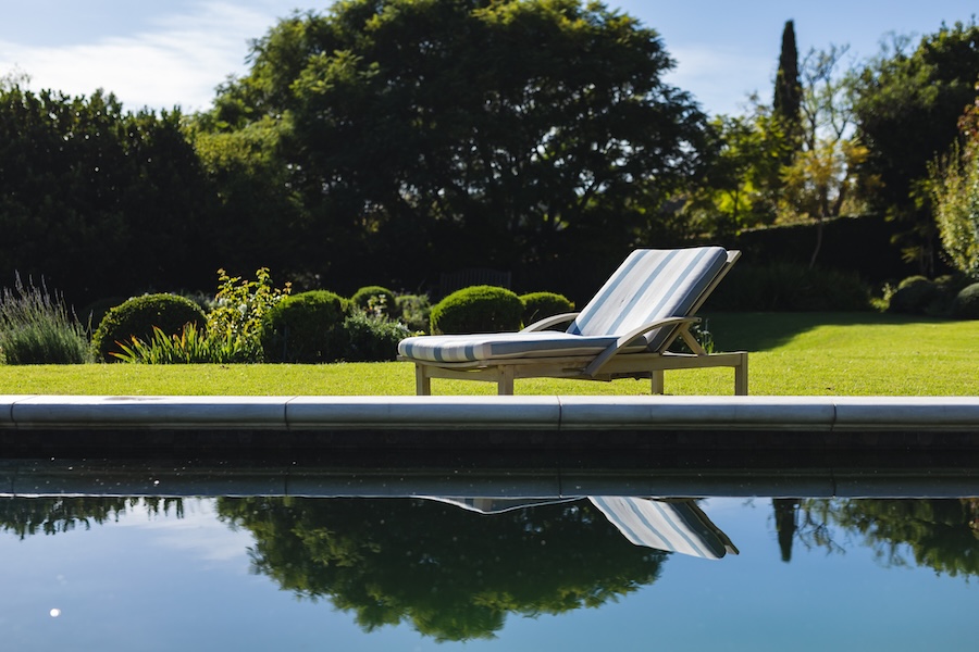 General view of tranquil swimming pool and deckchair with stunning mountains countryside.