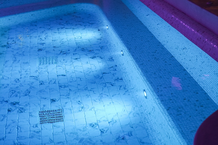 Small pool lights shining underwater at night.