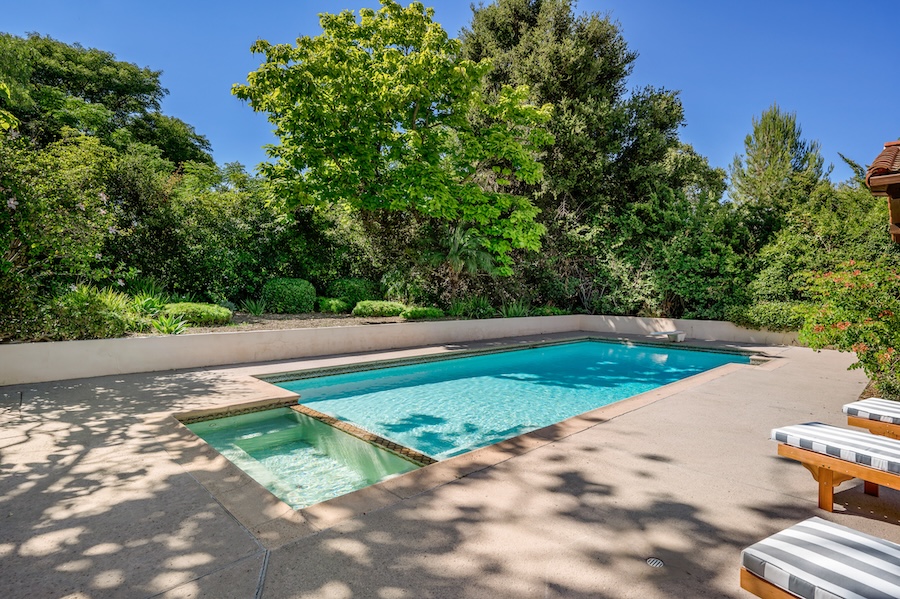 an-outdoor-pool-with-two-chairs-near-it-and-a-fence-surrounding-2