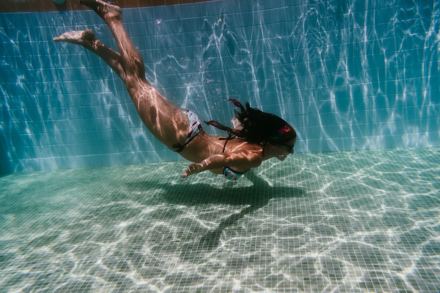 young woman diving underwater in a pool.