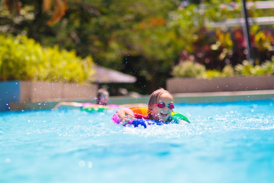 Child in swimming pool floating on toy ring.