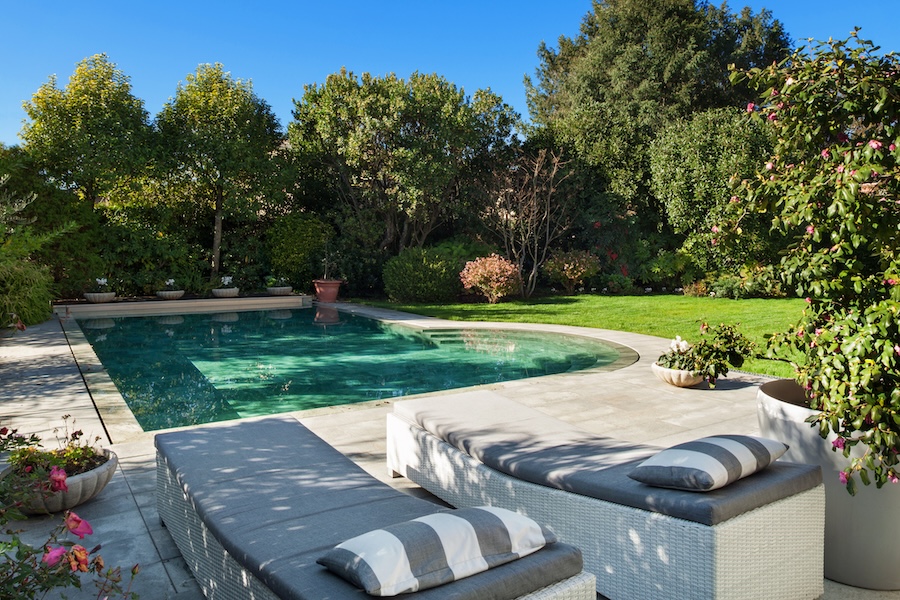 Green garden with a pool and two lawn chairs