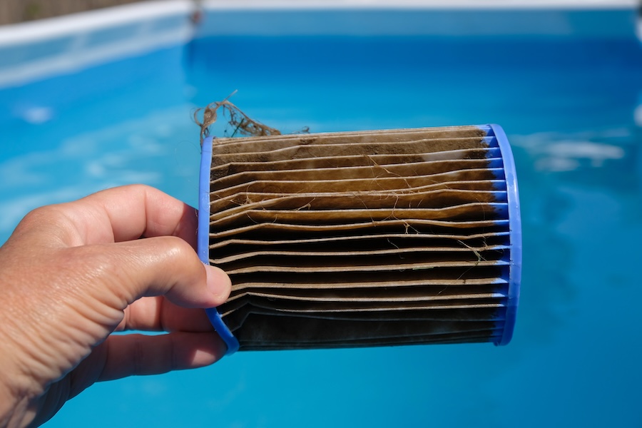 Dirty Replacement Pool Filter Cartridge in a woman's hand.