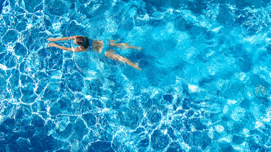 Active girl in swimming pool aerial drone view from above