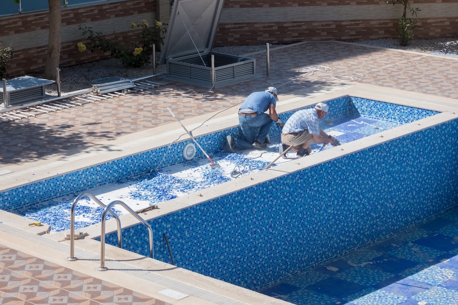 Two workers repairing a swimming pool