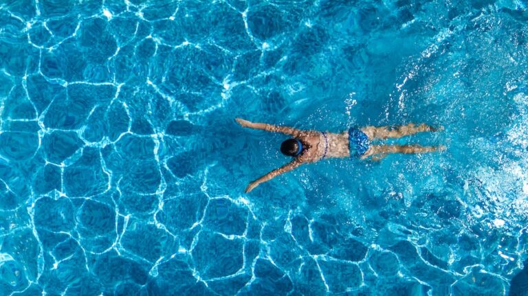 Aerial top view of woman in swimming pool water