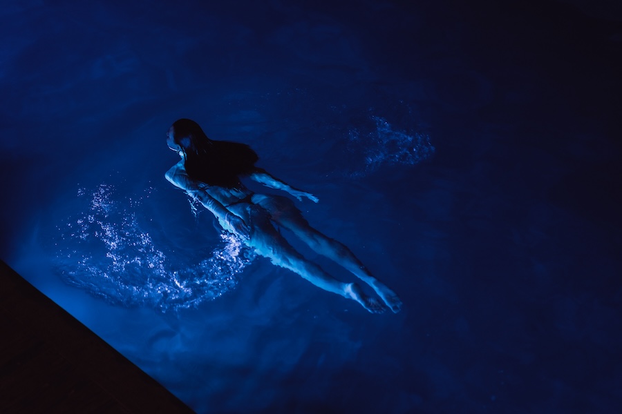 Calm beautiful young woman relaxing in a swimming pool at night