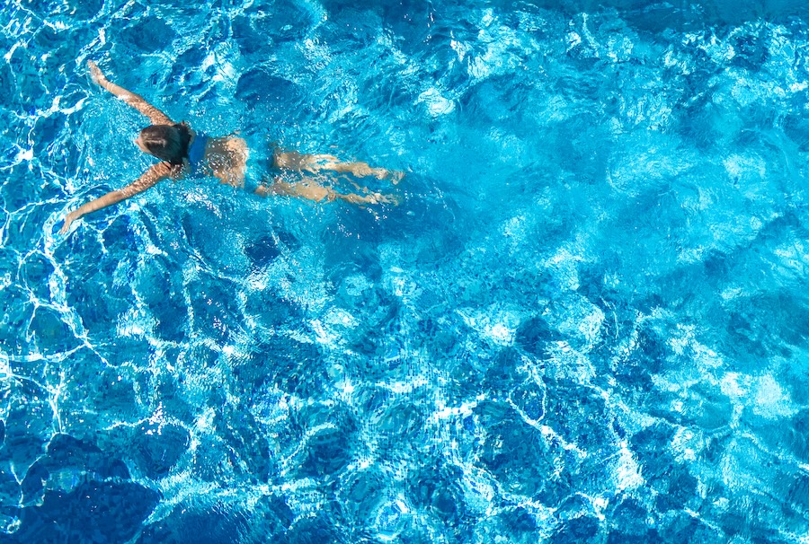 Active girl in swimming pool aerial drone view from above