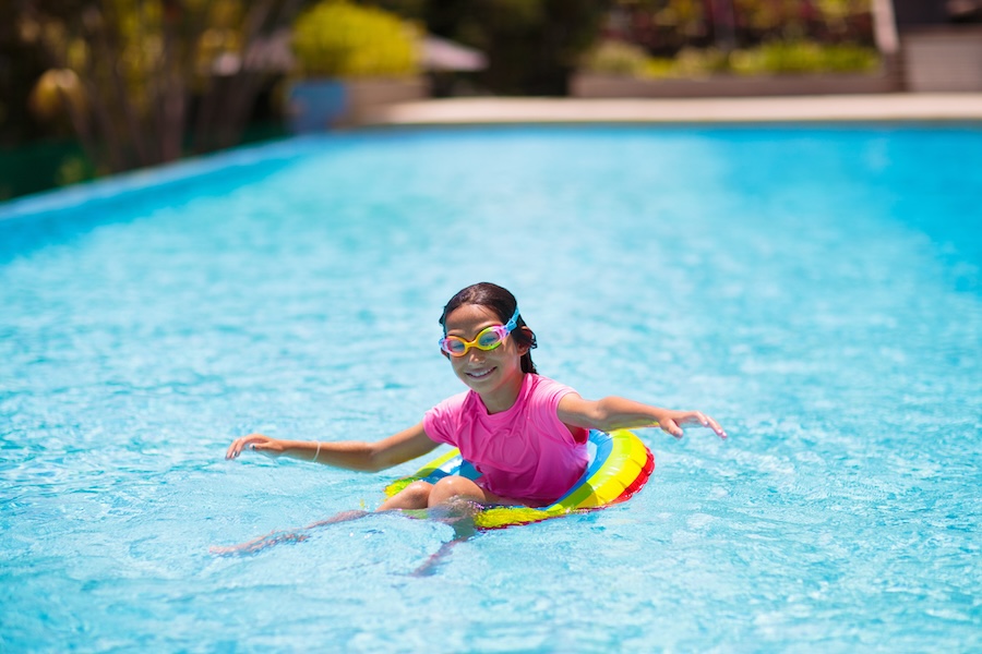 Child in swimming pool floating on toy ring.