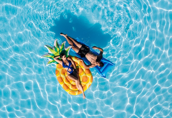 Young beautiful couple relaxing and enjoying vacation in the pool. Concept love, summer leisure, luxury, romance and tropical lifestyle.