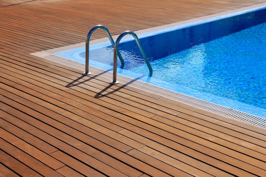 blue swimming pool with teak wood flooring