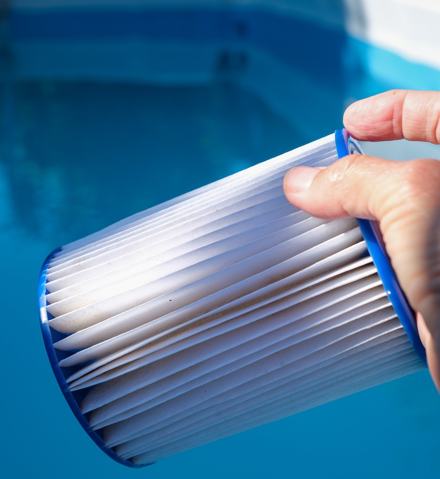 Replacement Pool Filter Cartridge in a Hand in Morning Sunlight. Filter Reuse. Family pool maintenance.