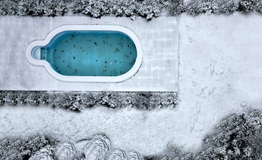 Above view of an uncovered pool surrounded by snow.