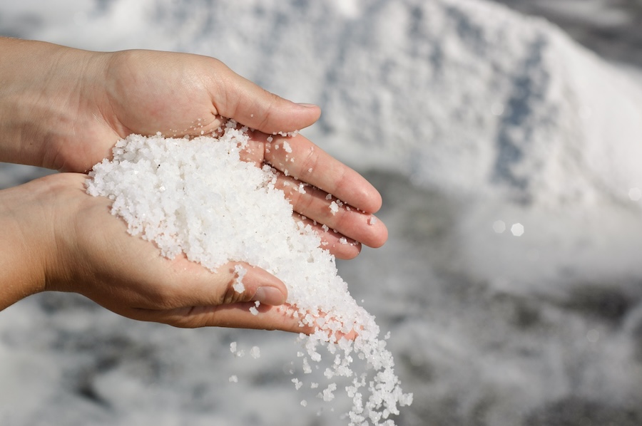 Woman scattering a pile of freshly harvested salt